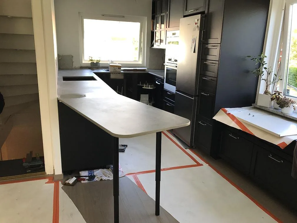 Köksbänkskiva i grå Dekton Kreta, honad betongton, monterad som halvö i ett kök under montering i Lund.
