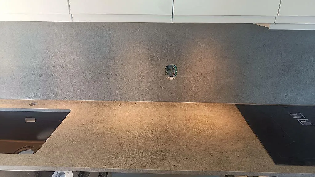 Köksbänkskiva i matt Dekton Kreta med svart diskho, svart häll och matchande stänkskydd i Malmö.