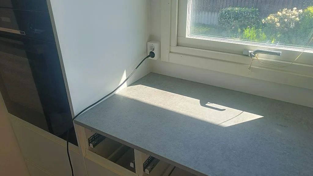 Separat bänkyta i matt grå Dekton Kreta under fönster vid högskåp i ett kök i Malmö.