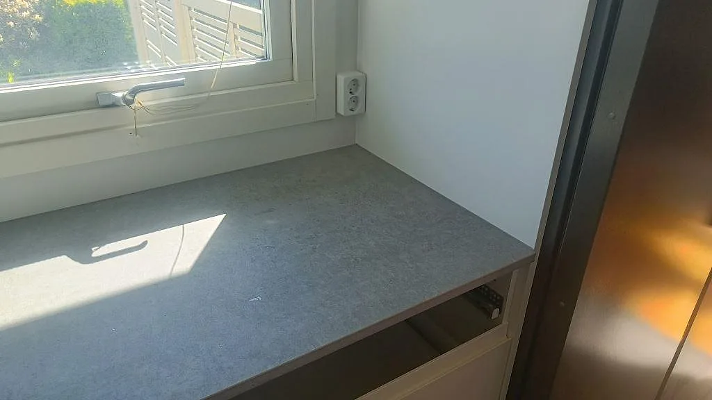 Installerad sidobänk i matt Dekton Kreta vid fönster med vit köksinredning i Malmö.