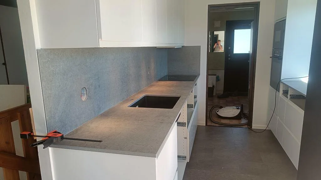 Köksbänkskiva i matt grå Dekton Kreta, 20 mm keramik, med matchande stänkskydd, svart diskho och häll i Malmö.