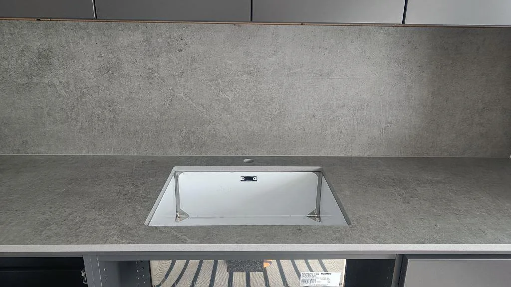 Underlimmad diskho i en grå Dekton Kreta köksbänkskiva med betongstruktur och stänkskydd i Mullsjö.