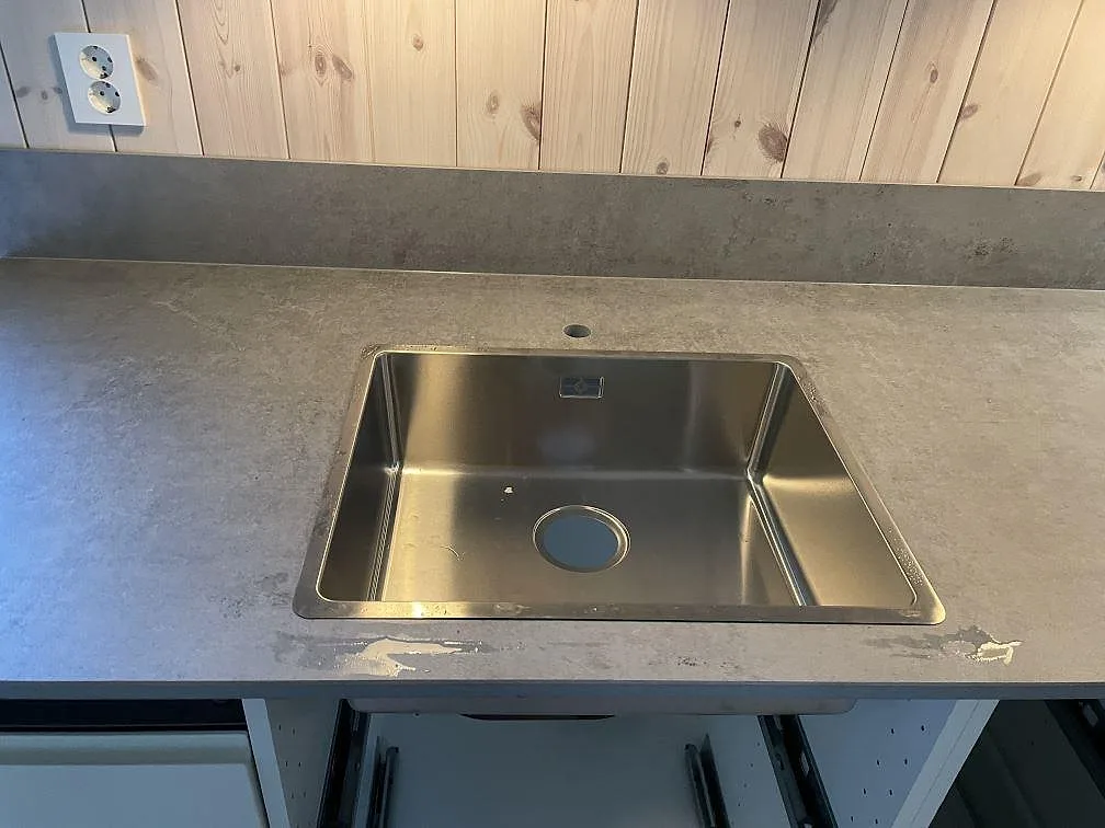 Närbild på matt Dekton Kreta köksbänkskiva i keramik med rostfri diskho och grått stänkskydd i Sösdala.