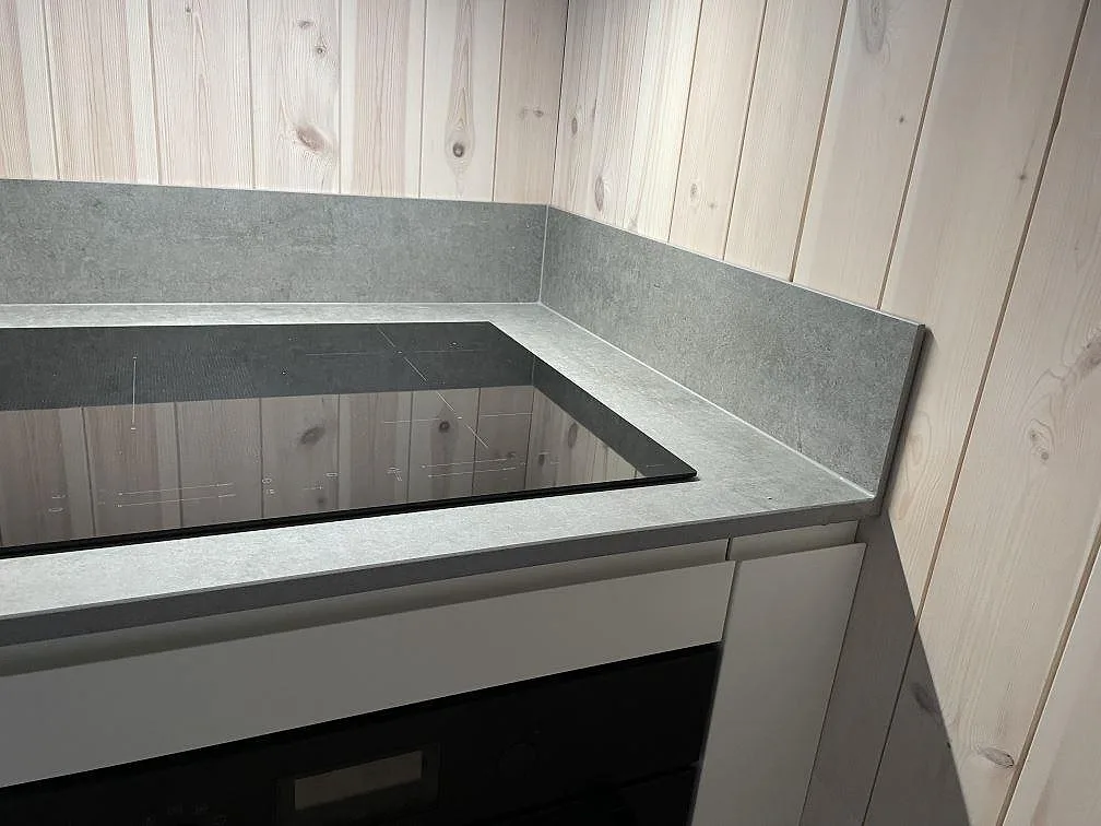 Detalj av svart induktionshäll i en matt Dekton Kreta bänkskiva med matchande stänkskydd i Sösdala.