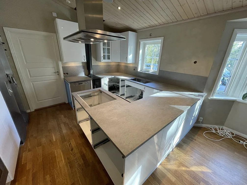 Monterad köksbänkskiva i Dekton Kreta, matt, med sammanhängande arbetsytor och stänkskydd längs väggen i Vendelsö.