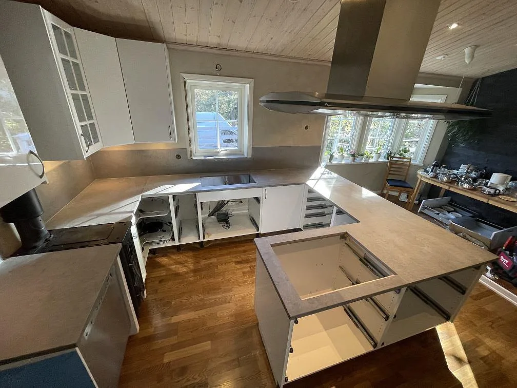 Översikt över kök i Vendelsö med matt Dekton Kreta på bänkskivor, väggnära stänkskydd och öppna köksstommar under montering.
