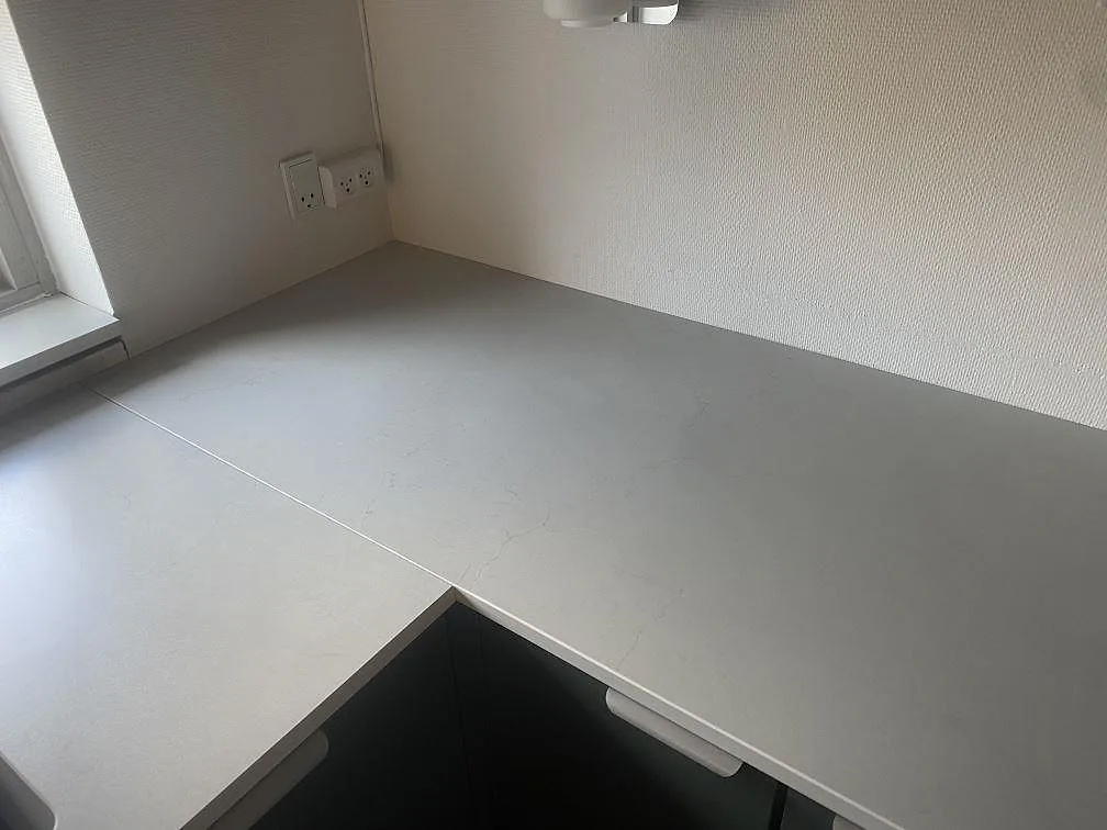 Hörnmonterad köksbänkskiva i matt Dekton Laguna Velvet med ljusgrå keramikyta vid vägg i Hvidovre.
