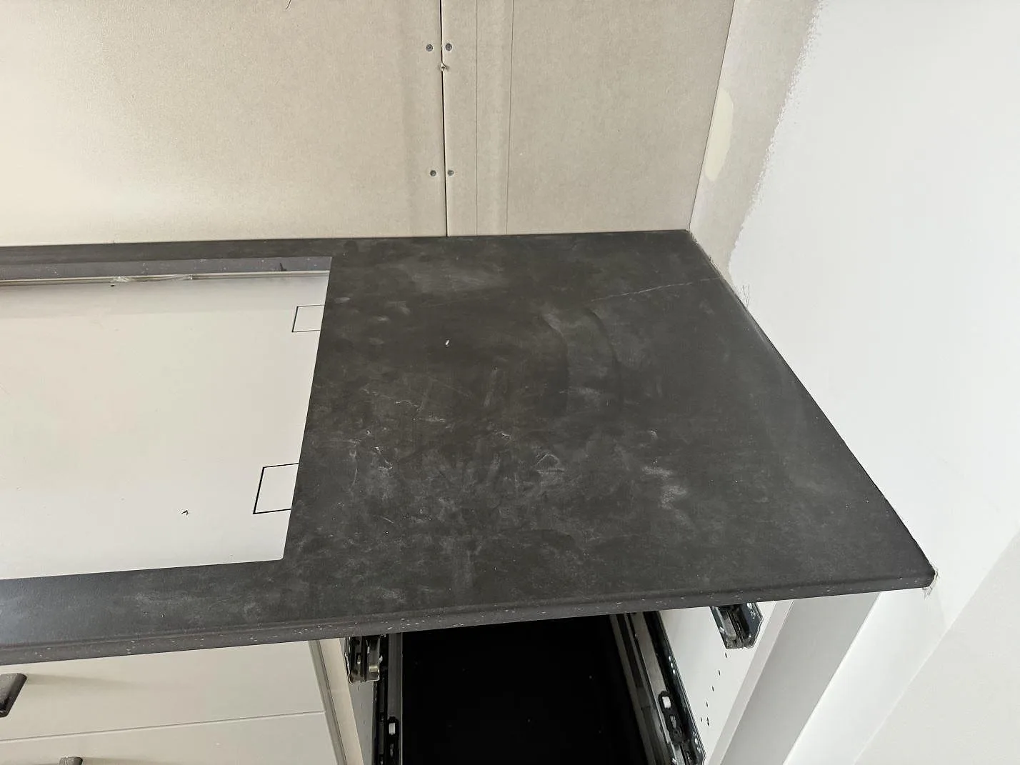 Detalj av matt Dekton Laos vid väggbänk och öppen lådstomme i ett kök under montering i Halmstad.