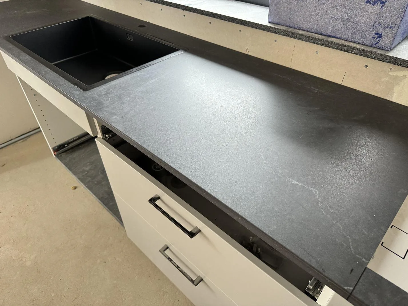 Köksbänkskiva i matt Dekton Laos med svart underlimmad diskho och vit köksinredning i Halmstad.