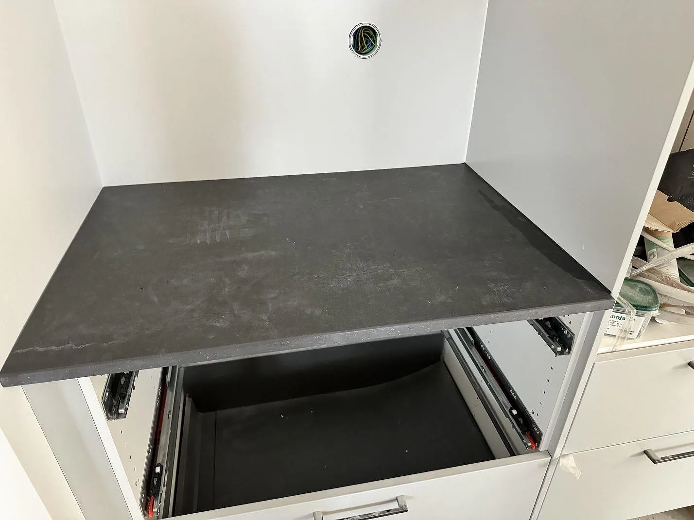 Rak bänkyta i matt Dekton Laos med mörk sten, vita stommar och öppen låda i Halmstad.