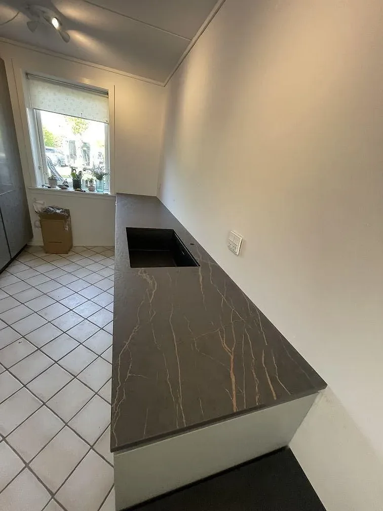 Bänkrad i Dekton Laurent med urtag för diskho och fönster, matt mörk keramik i ett kök i Allerød.