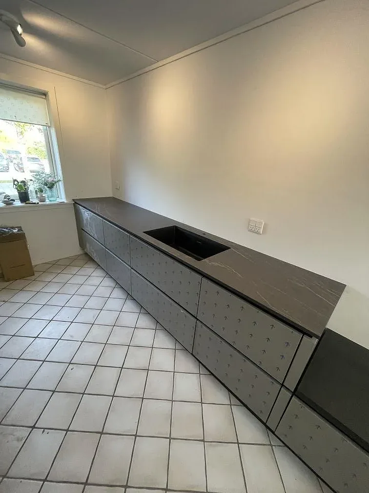 Bänkrad i Dekton Laurent med stänkskydd och köksstommar under montering, matt mörk keramik i ett kök i Allerød.