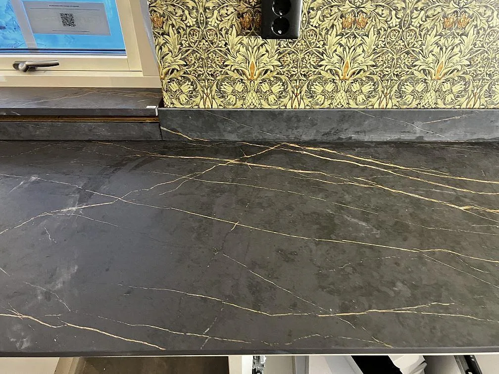 Matt Dekton Laurent som köksbänkskiva med uppvikt stänkkant, fönsterbänk och tydlig guldådring i Gränna.