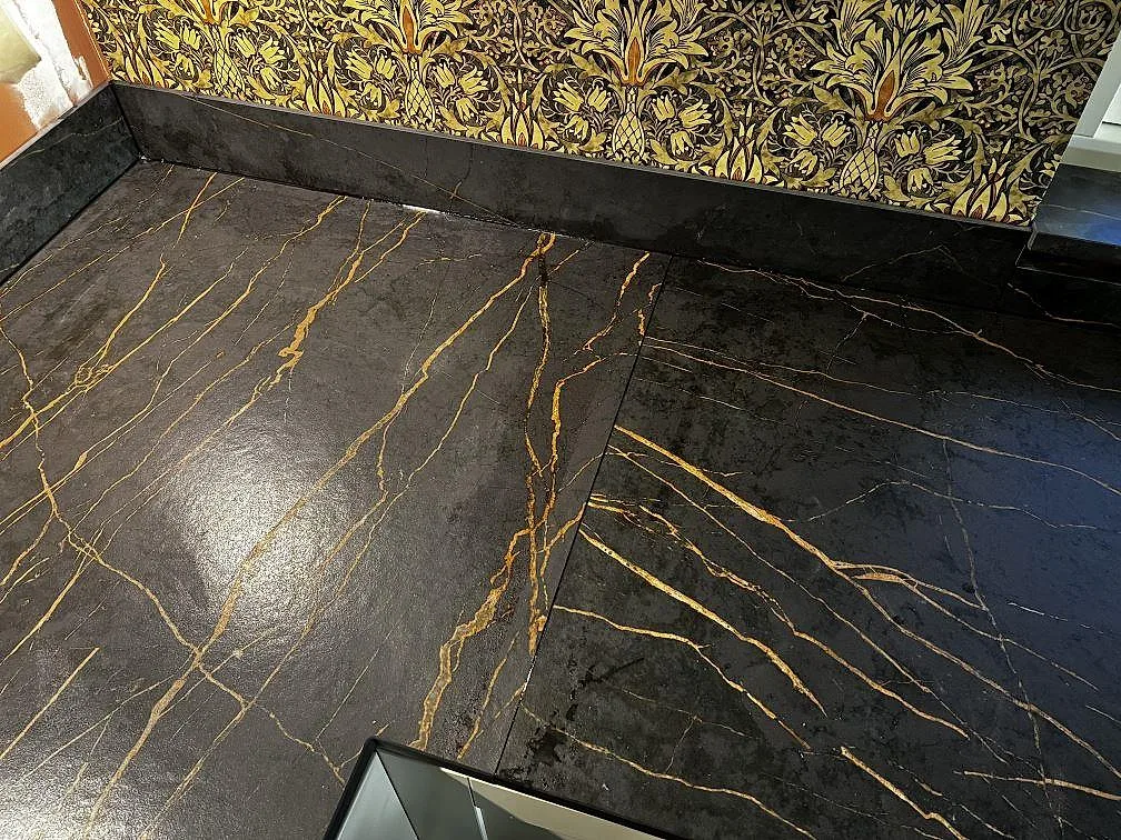 Hörndel av köksbänkskiva i matt Dekton Laurent keramik med uppvikt stänkkant och blommig tapet i Gränna.