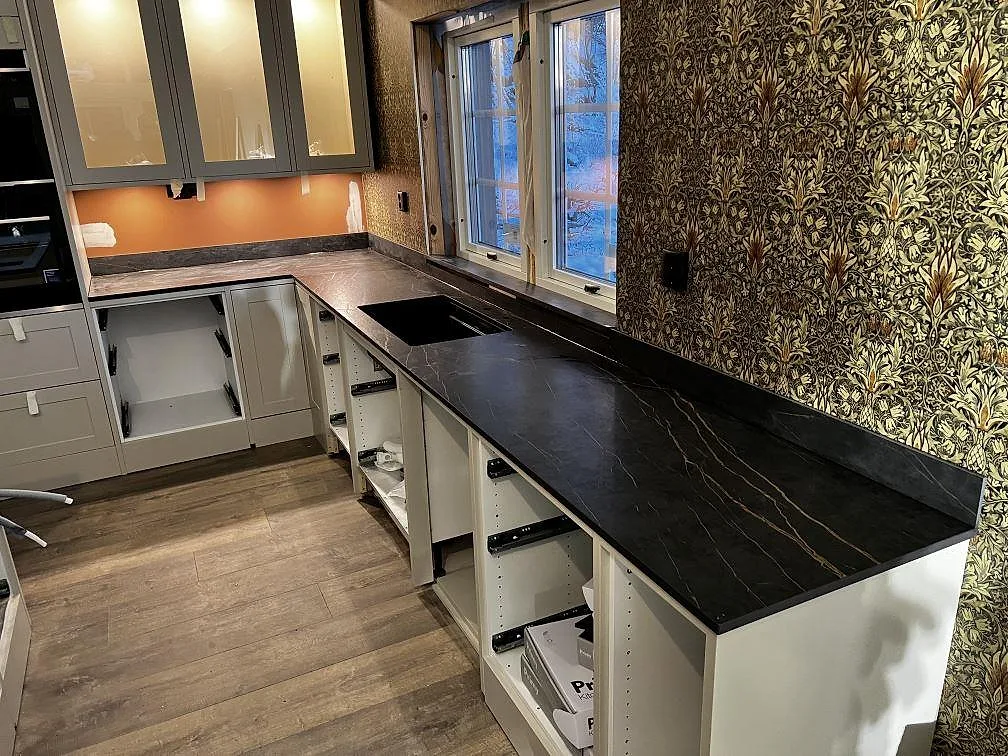 Köksbänkskiva i matt Dekton Laurent keramik med svart guldådring, underlimmad svart diskho, fönsterbänk och stänkkant i ett kök i Gränna.