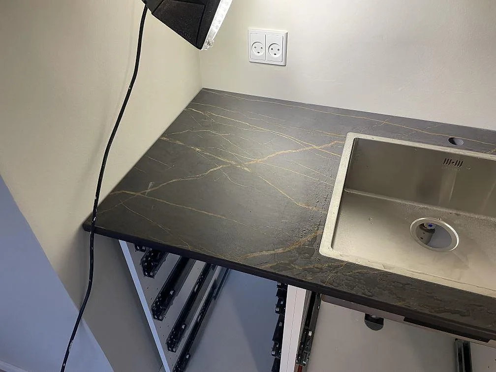 Hörn av köksbänkskiva i Dekton Laurent med rostfri underlimmad diskho och guldådrig matt keramik, kök under montering i København S.