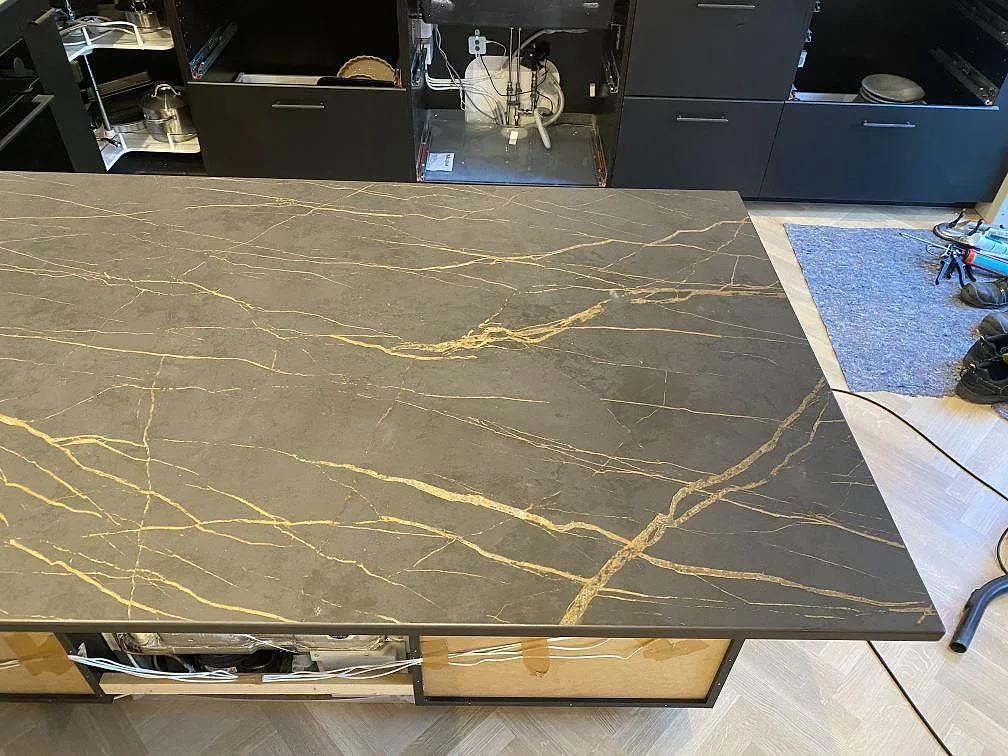 Köksbänkskiva i Dekton Laurent, matt grå keramik med gyllene ådring, med heltäckande stänkvägg i samma sten i ett kök i Limhamn.