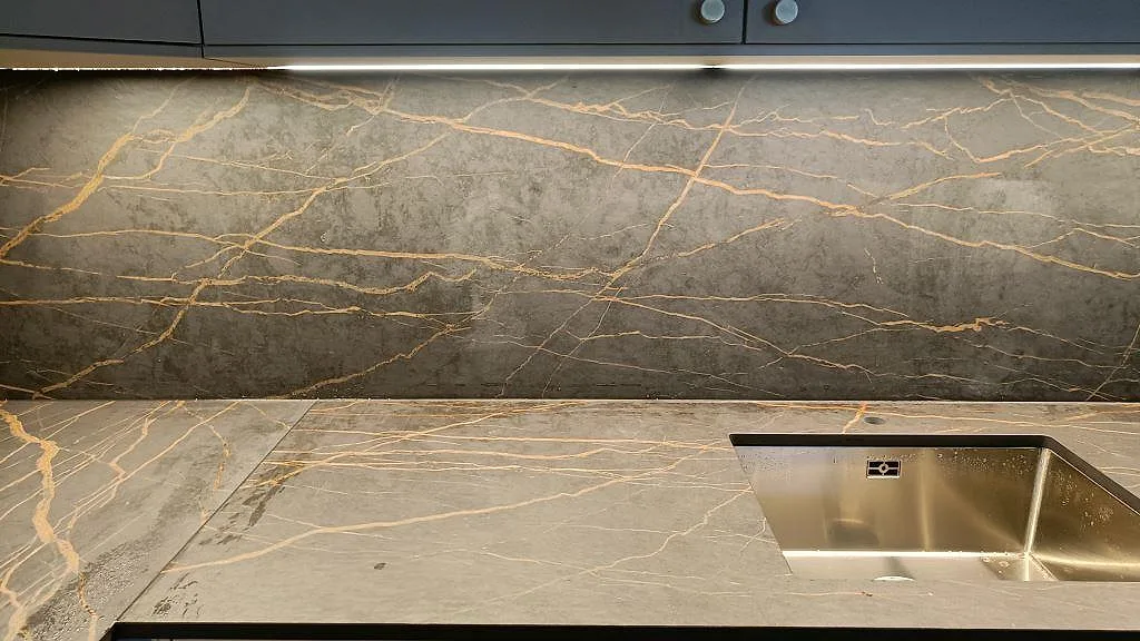 Dekton Laurent köksbänkskiva i matt utförande med underlimmad rostfri diskho och dramatisk guldädring i ett kök i Malmö.