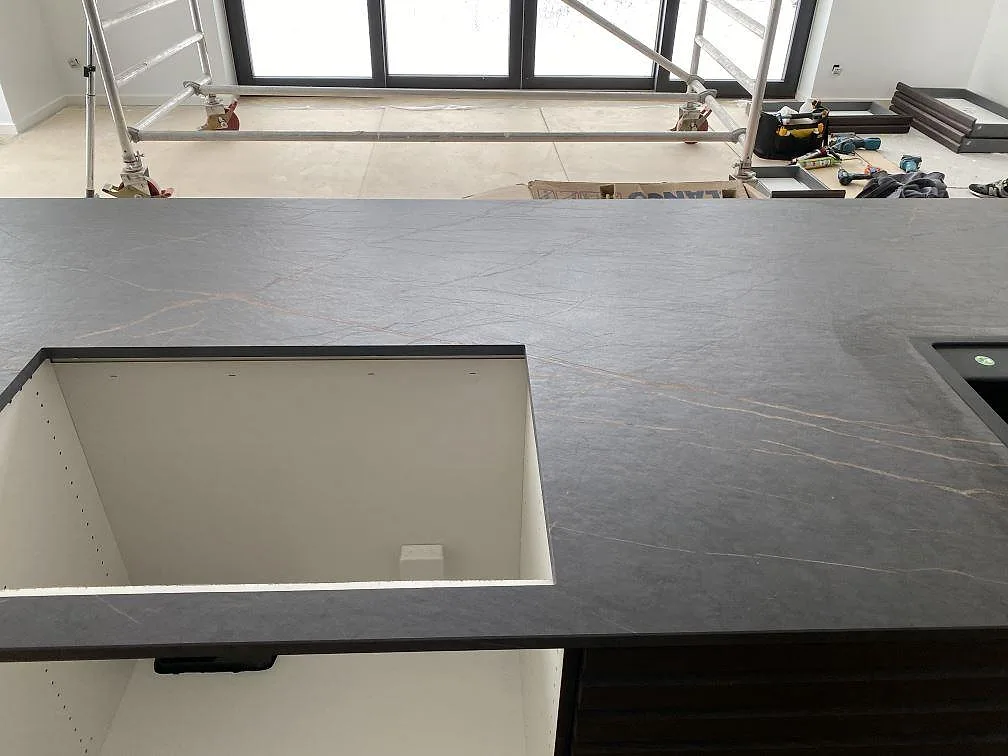 Köksbänkskiva i matt Dekton Laurent med rektangulärt hälluttag och mörk ådring i ett kök i Odense NØ.