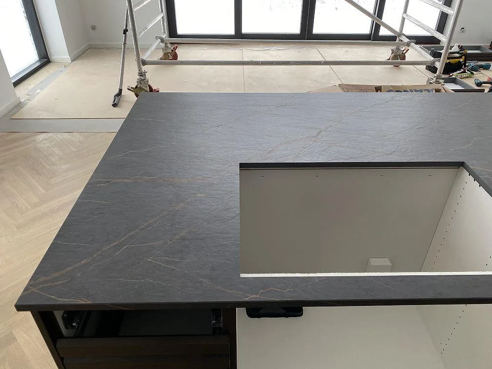 Stor yta av matt Dekton Laurent på köksö med hälluttag och fiskbensgolv under montering i Odense NØ.
