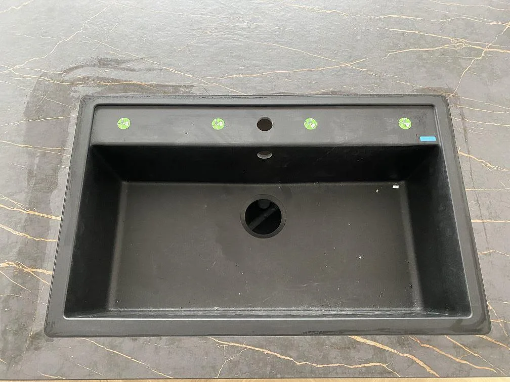 Detalj av svart diskho ovanpå matt Dekton Laurent, mörk keramik med varm ådring i Odense NØ.