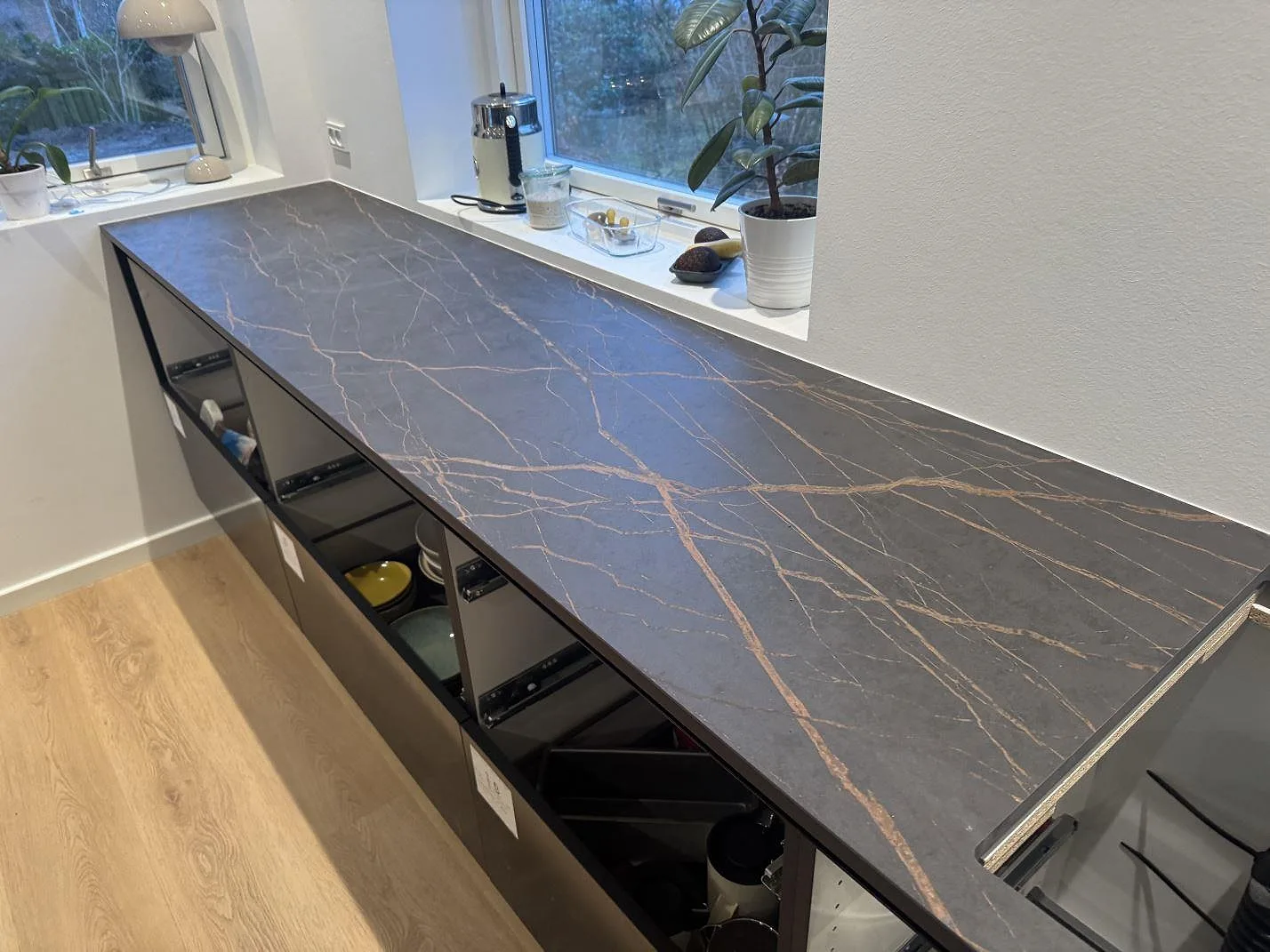 Väggbänk i Dekton Laurent med matt keramisk yta och ljus ådring längs fönsterpartiet i ett kök i Odense SV.