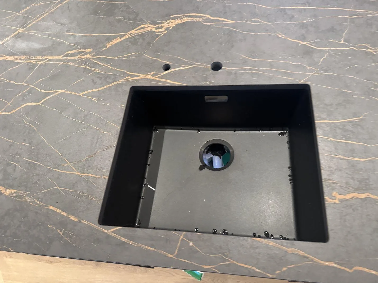 Detalj av matt Dekton Laurent kring ett rektangulärt urtag i köksön, med två mindre borrhål synliga i Odense SV.