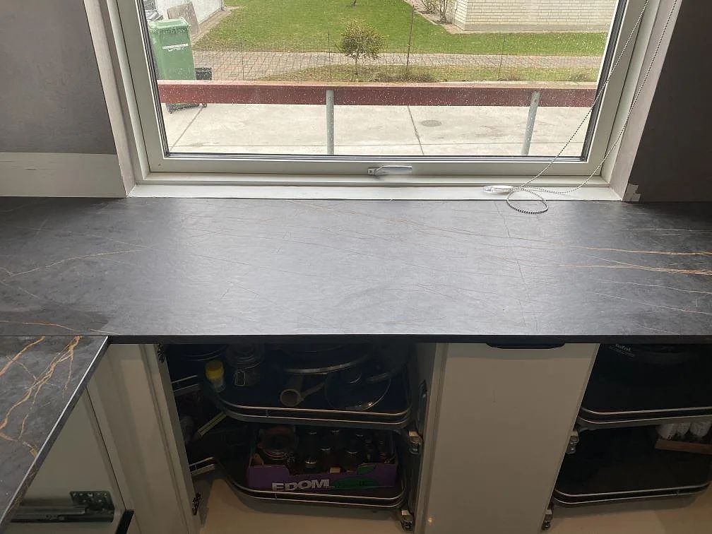 Fönsterbänk och bänkskiva i Dekton Laurent med diskret guldådring i matt mörk keramik i ett kök i Vallensbæk.