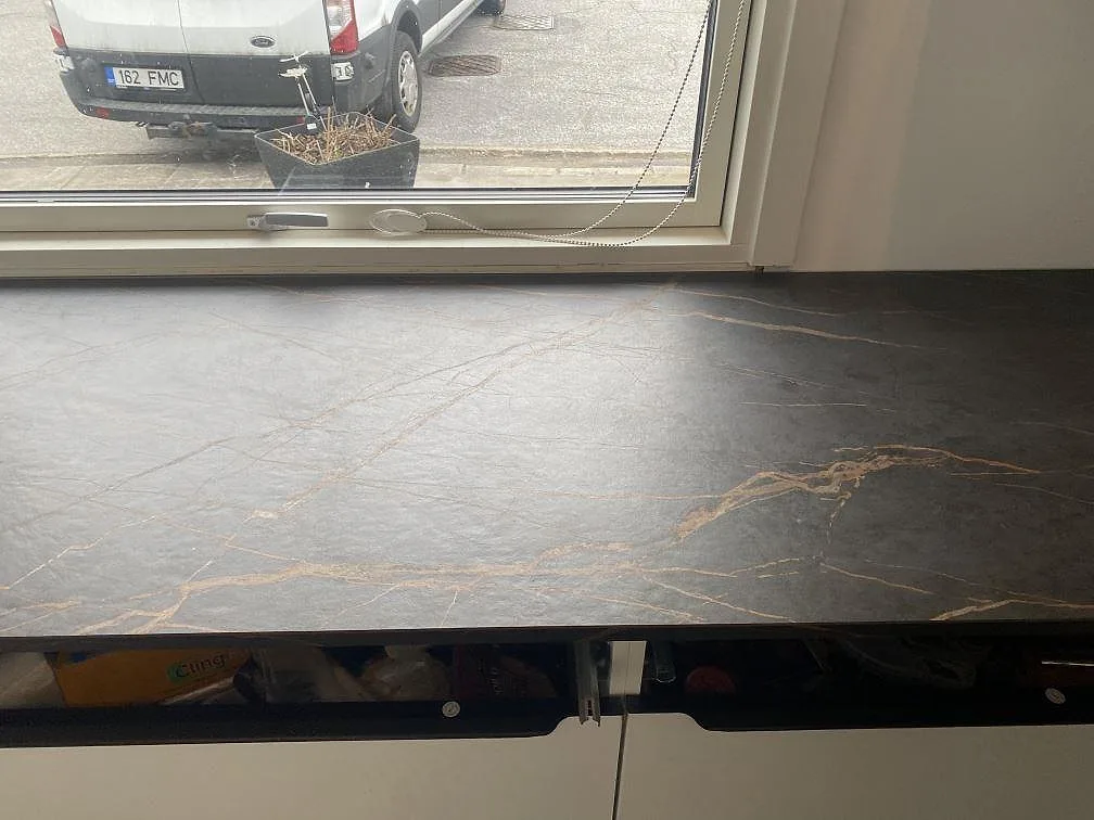 Köksbänkskiva i matt Dekton Laurent vid fönster, mörk keramik med varm guldådring i ett kök i Vallensbæk.