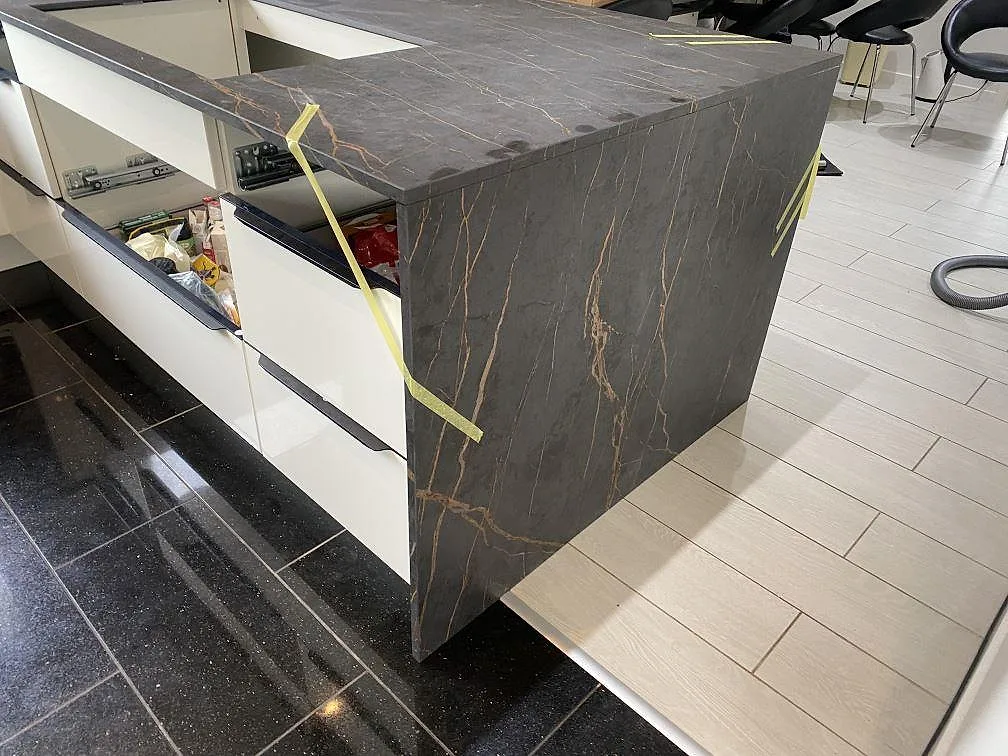 Vattenfallskant på köksö i Dekton Laurent där den varma guldådringen löper ner över den matta keramiksidan i ett kök i Vallensbæk.