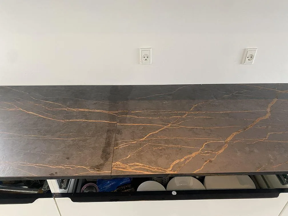 Nedvy över köksbänkskiva i Dekton Laurent med slingrande guldådror mot mörk matt keramik i ett kök i Vallensbæk.
