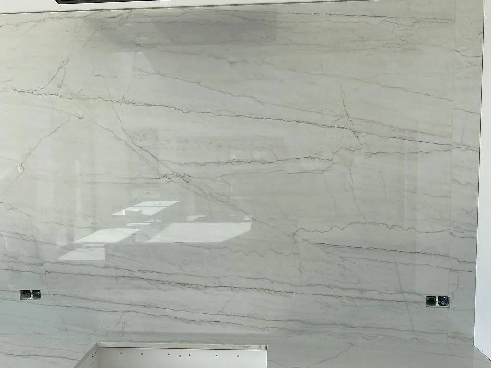 Närbild på polerad Dekton Limbo keramik som stänkvägg med eluttag och sammanhängande ådring i köket i Brøndby.