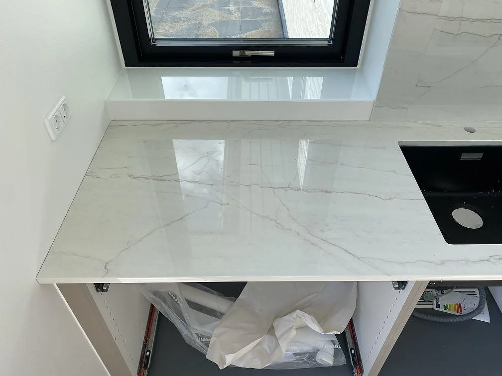 Polerad Dekton Limbo keramik som bänkskiva vid fönster med svart diskho och matchande väggbeklädnad i Brøndby.