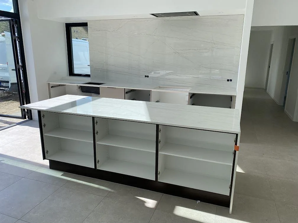 Köksbänkskivor i polerad Dekton Limbo keramik med köksö och hög väggbeklädnad under montering i Brøndby.