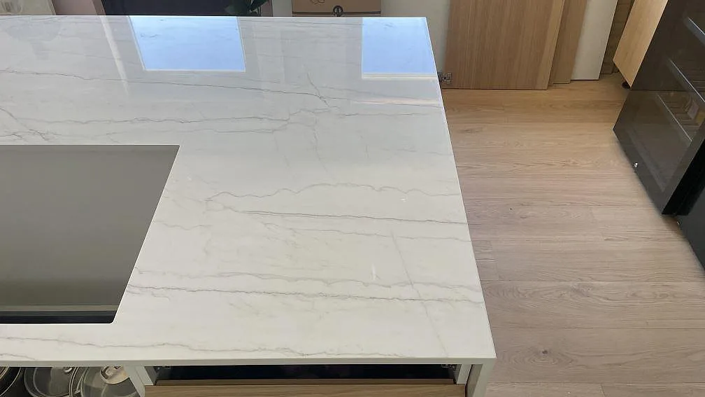 Blank polerad Dekton Limbo bänkskiva med rektangulär öppning, reflektioner och ljus köksinredning i Bunkeflostrand.