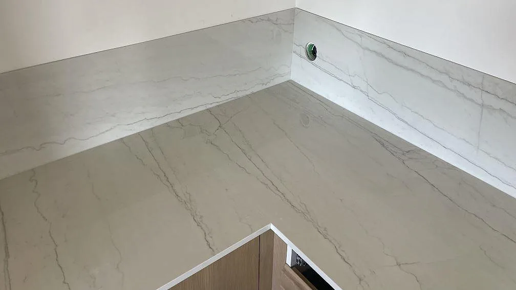 Polerad Dekton Limbo keramik som bänkskiva och låg stänkkant längs hörnet i ett kök i Bunkeflostrand.