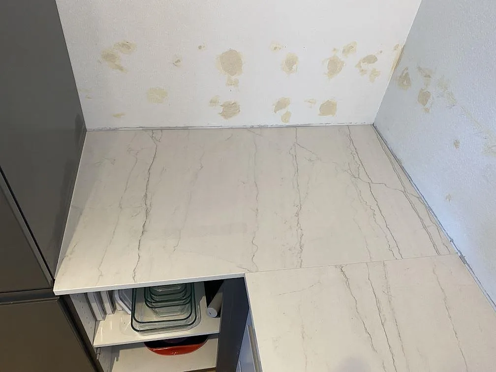 Närbild på skivänden i polerad Dekton Limbo, 20 mm, med marmorlik grå ådring mot en oinredd köksvägg i København s.