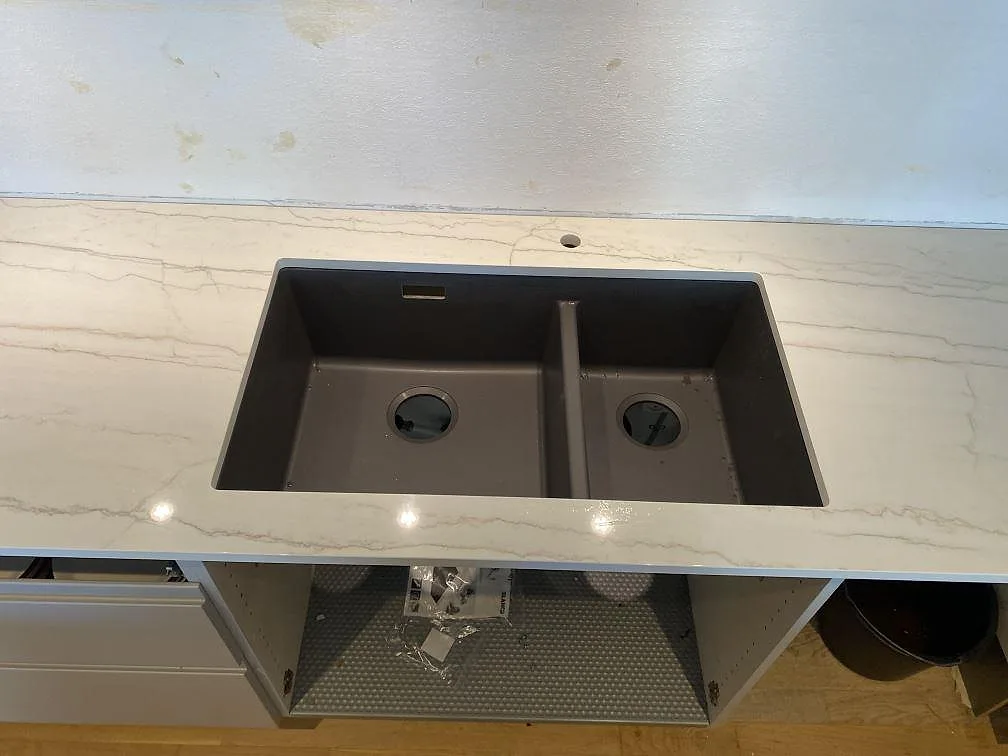 Närbild på polerad Dekton Limbo runt diskbänksdelen, med blank yta och grå ådring i ett kök i København s.