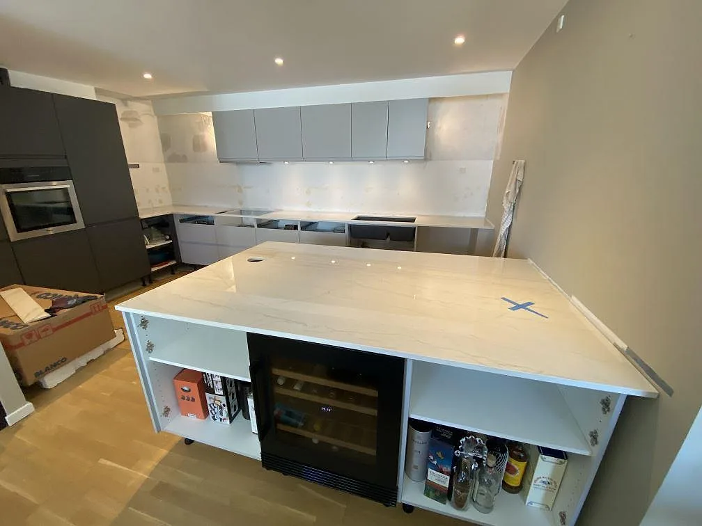 Köksbänkskiva i polerad Dekton Limbo, 20 mm keramik med ljus grå ådring, monterad på väggbänk och halvö i ett kök i København s.