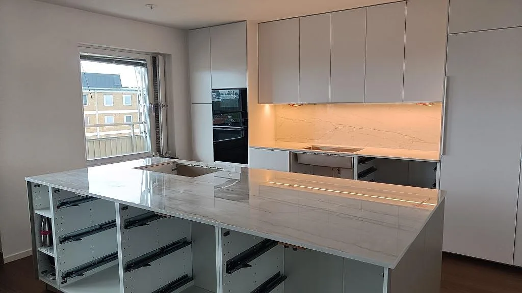 Köksbänkskiva i polerad Dekton Limbo keramik över köksö och väggbänk med matchande väggbeklädnad i malmö.