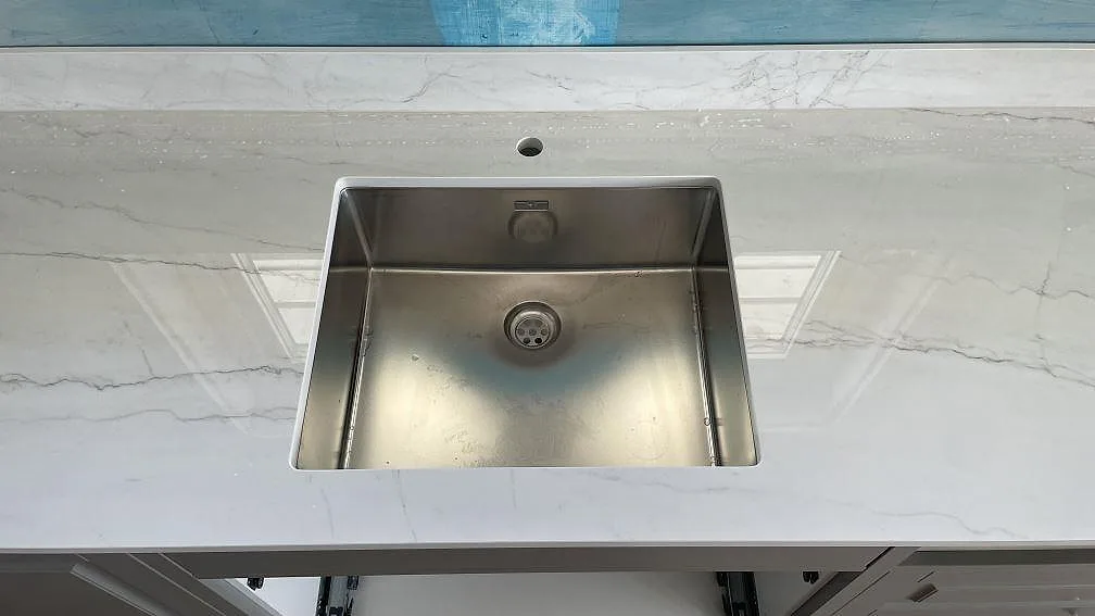 Underlimmad rostfri diskho i polerad Dekton Limbo med blandarhål och matchande stänkkant i Örby.