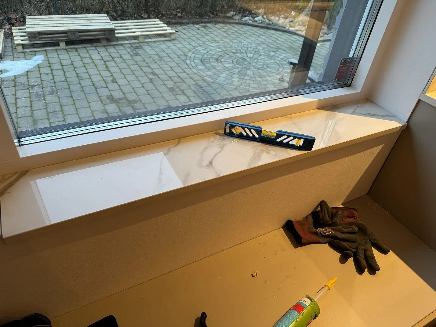 Polerad fönsterbänk i Dekton Lucid keramik med Calacatta-liknande mönster vid stort fönster i Löddeköpinge.