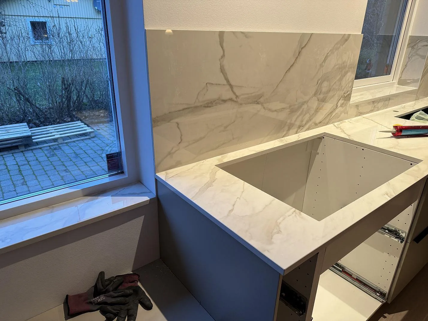 Bänkskiva, stänkskydd och fönsterbänk i polerad Dekton Lucid keramik med synlig grå ådring i Löddeköpinge.