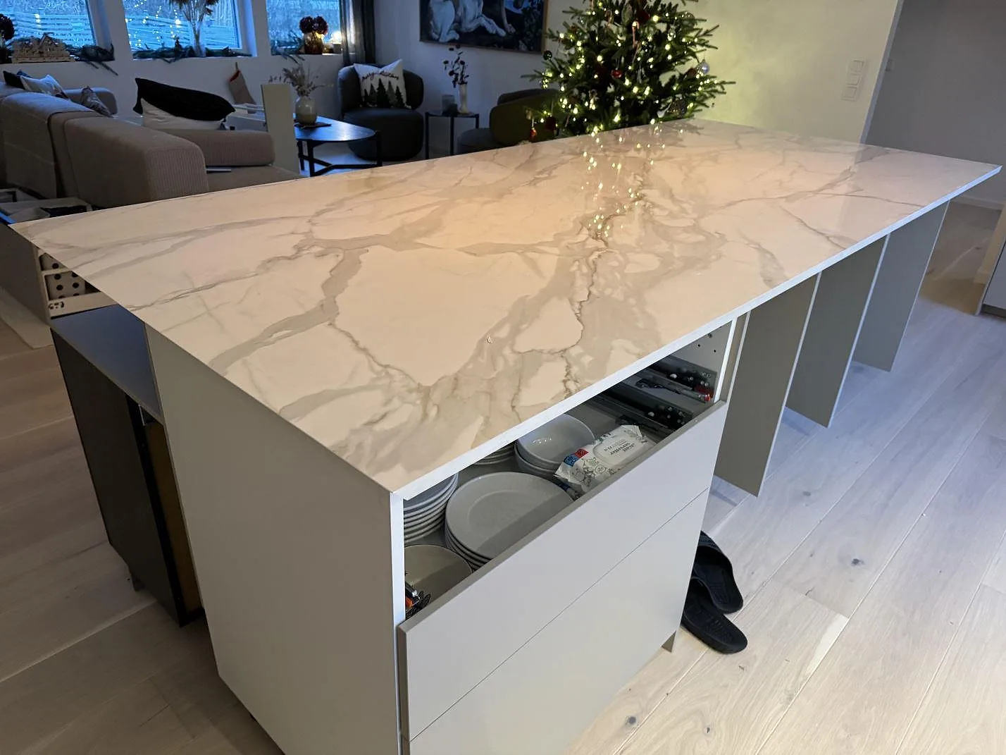 Köksö i polerad Dekton Lucid keramik med Calacatta-liknande ådring och julgran i bakgrunden i Löddeköpinge.