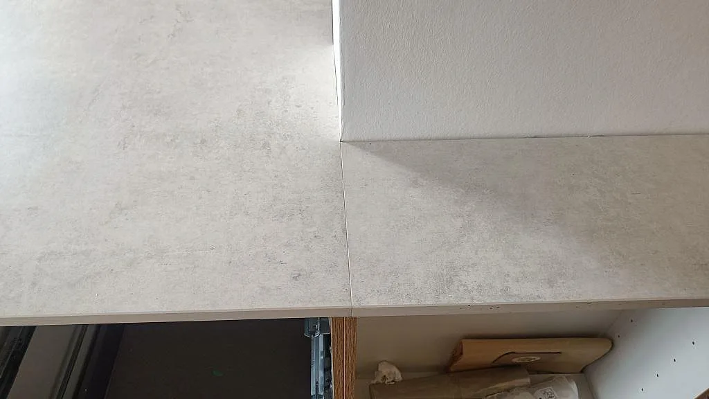 Detalj av skarv och matt yta i Dekton Lunar, 20 mm keramik, på köksbänk under montering i København Ø.