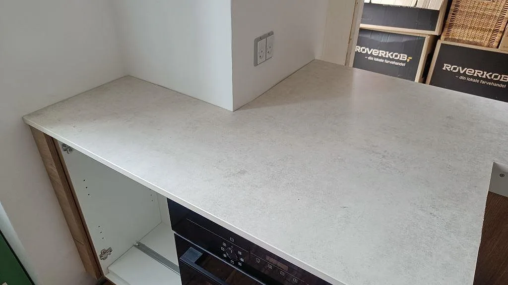 Matt Dekton Lunar på sidobänk med ljus stenyta, vägguttag och träskåp under montering i København Ø.