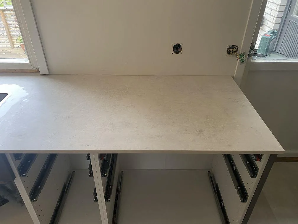 Ljusgrå köksbänkskiva i matt Dekton Lunar över öppna köksstommar under montering i Sävedalen.