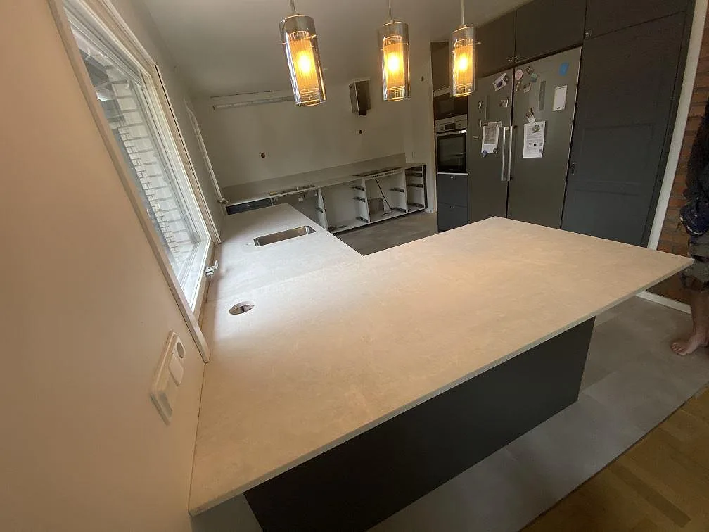 Kök i Sävedalen med stor köksö och väggbänkar i matt Dekton Lunar under montering.