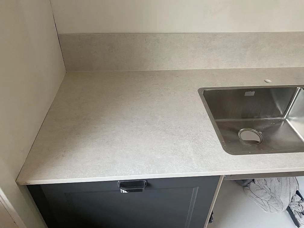 Hörnsektion av köksbänkskiva i matt Dekton Lunar med underlimmad rostfri diskho och uppvikt stänkkant i Sävedalen.