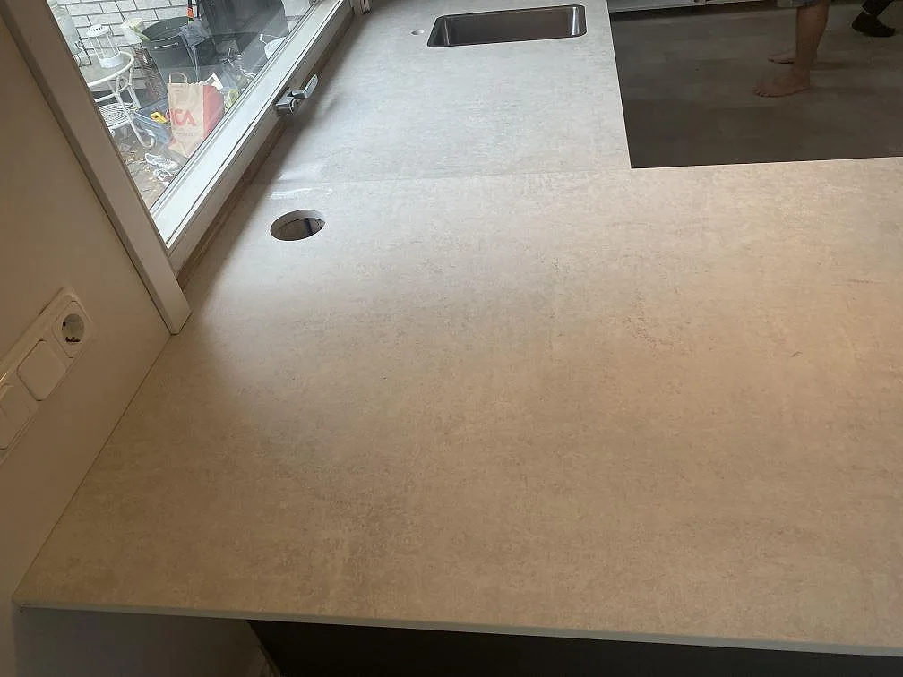 Köksbänkskiva i matt grå Dekton Lunar med urtag för blandare och underlimmad rostfri diskho i ett kök i Sävedalen.